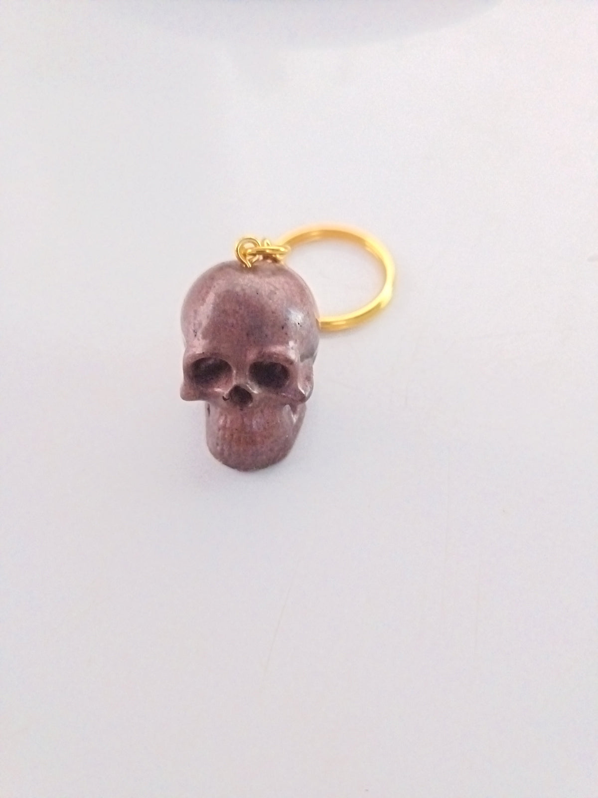 Porte-clé tête de mort sculptée en résine mauve-bordeaux avec anneau doré