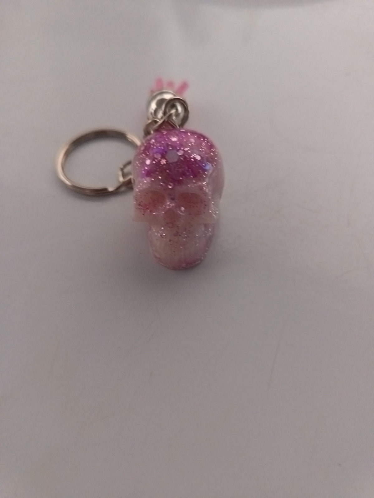 Porte-clé tête de mort sculptée en résine violet-rose translucide avec paillettes irisées
