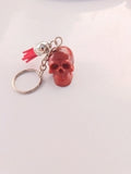 Porte-clé tête de mort en résine rouge translucide avec grelot argenté et pompon rouge