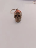 Porte-clé tête de mort sculptée en résine bronze-brun avec paillettes oranges-rouges