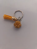 Porte-clé patte de chien sculptée en résine caramel avec pompon jaune moutarde