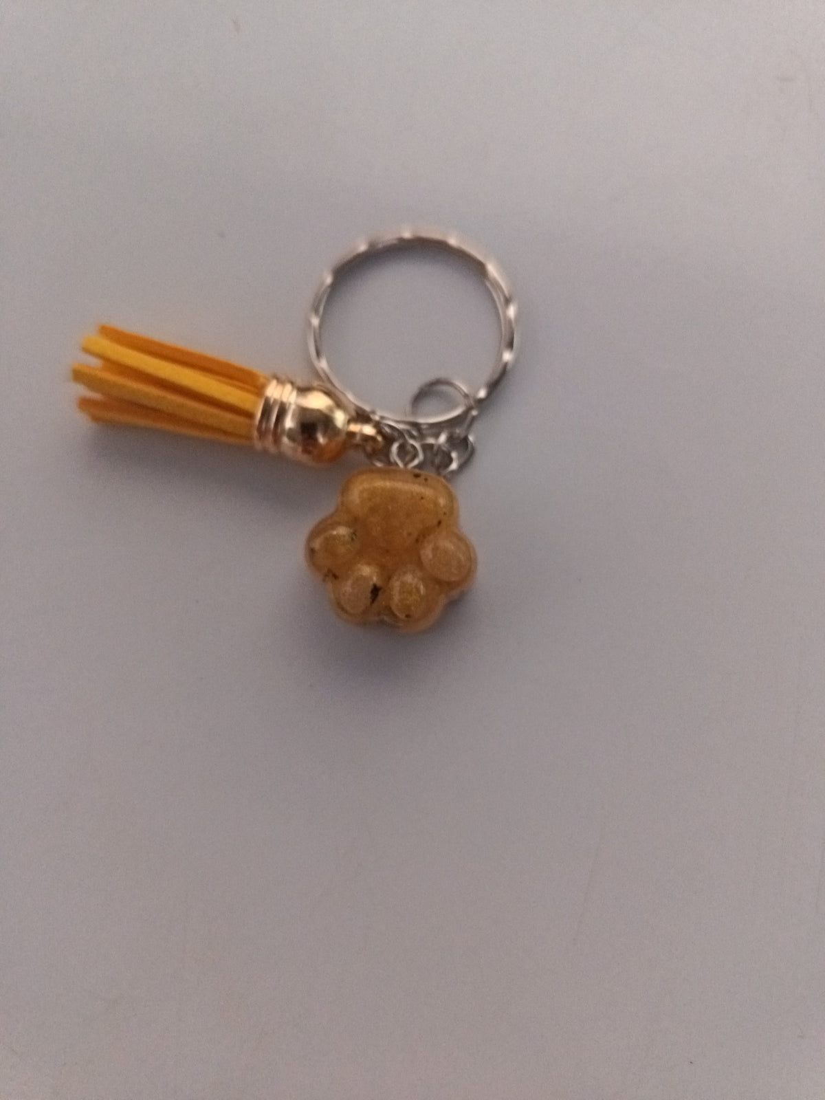 Porte-clé patte de chien sculptée en résine caramel avec pompon jaune moutarde
