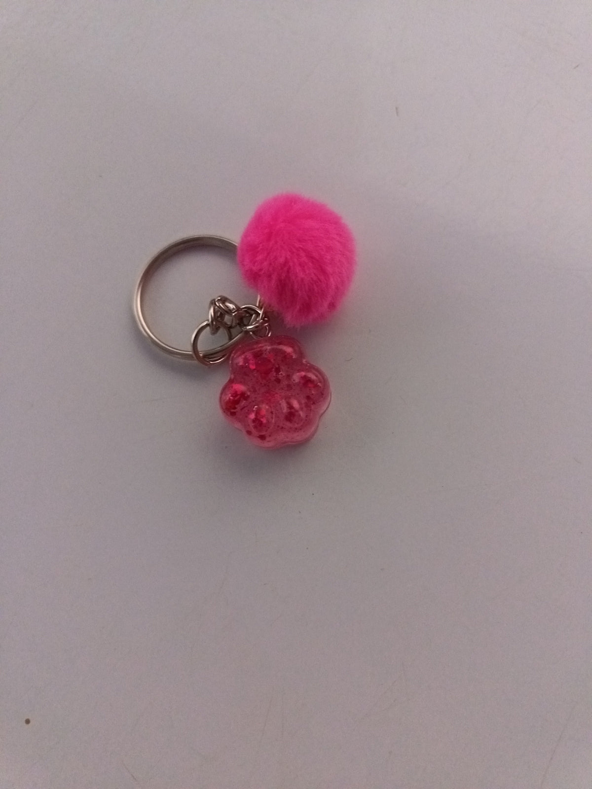 Porte-clé patte de chien sculptée en résine rose fuchsia avec pompon fourrure rose fuchsia