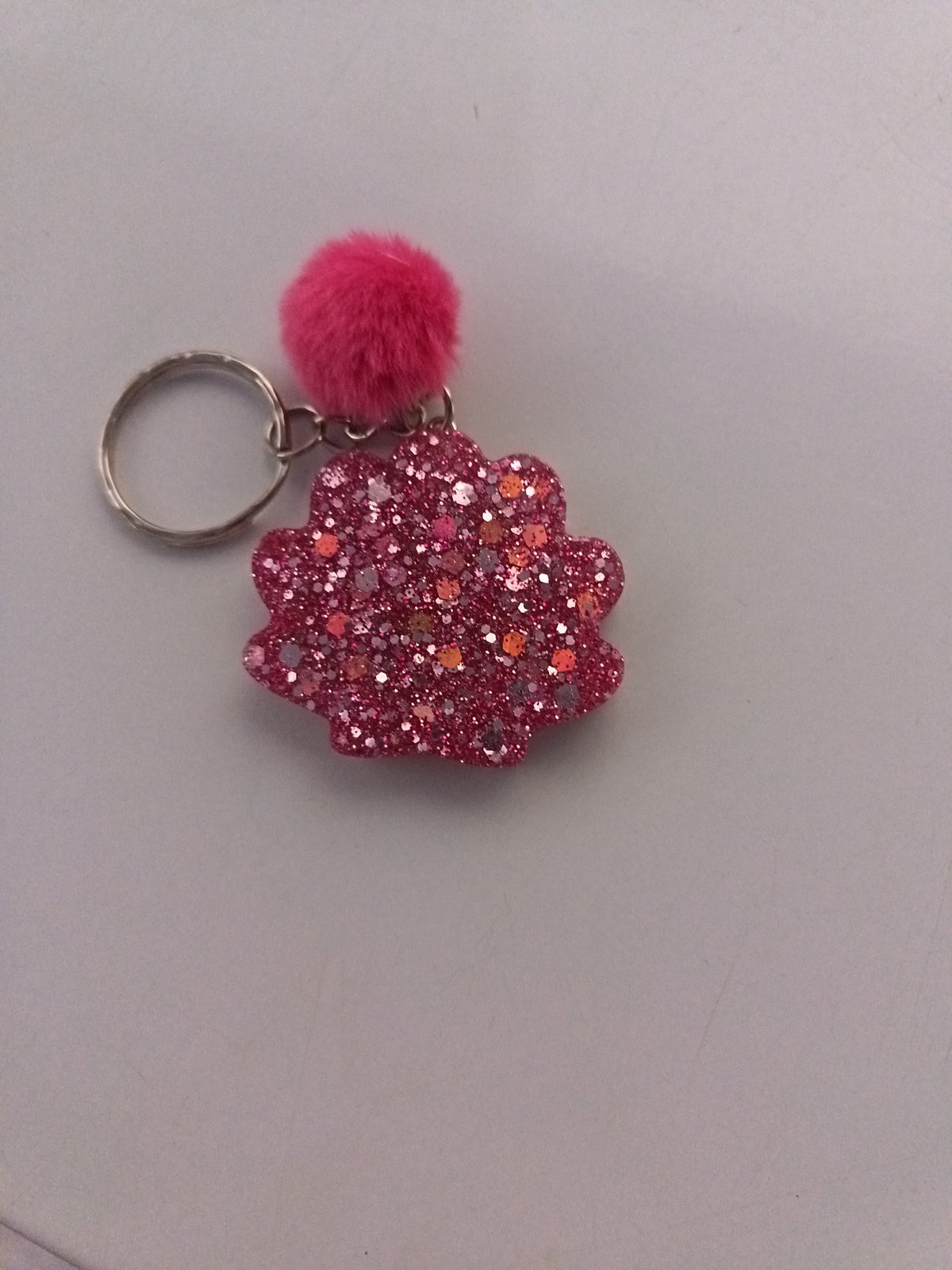Porte-clé coquillage en résine rose ultra-pailleté avec pompon fourrure rose fuchsia