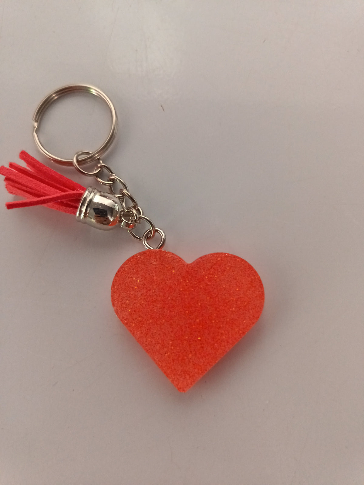 Porte-clé cœur en résine orange translucide pailleté avec pompon suédine rouge corail