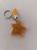 Porte-clé étoile en résine orange-dorée pailletée avec pompon suédine jaune moutarde