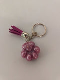 Porte-clé patte de chien sculptée en résine rose nacrée avec pompon suédine fuchsia