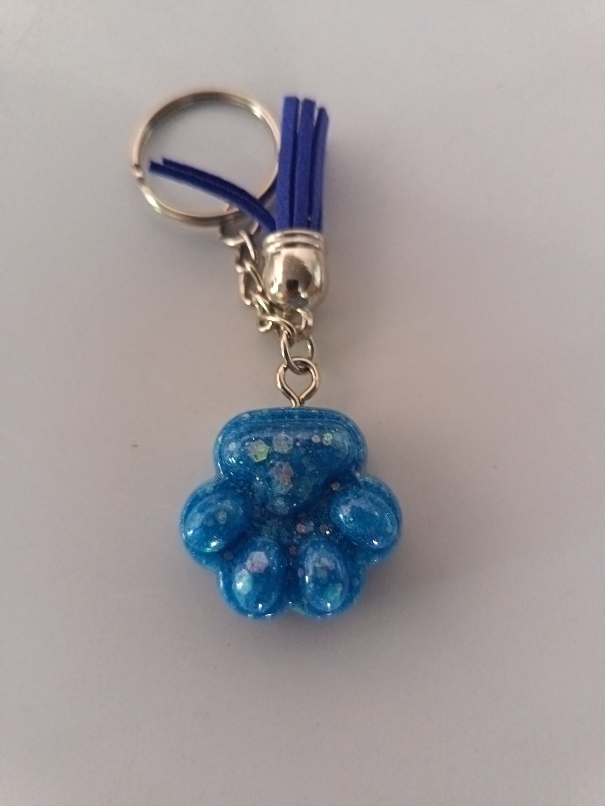 Porte-clé patte de chien sculptée en résine bleu turquoise irisé avec pompon suédine bleu roi