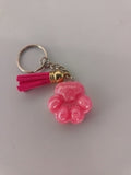 Porte-clé patte de chien sculptée en résine rose bonbon nacré avec pompon suédine fuchsia et breloque dorée