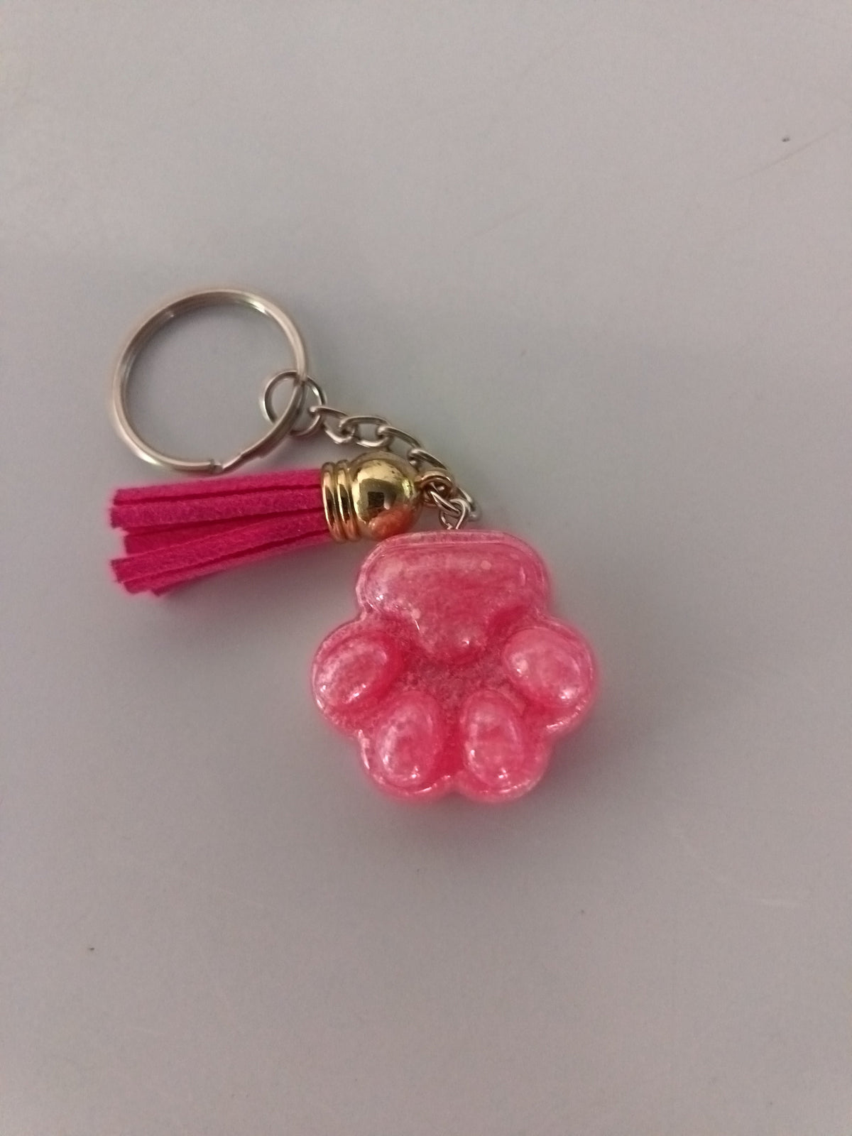 Porte-clé patte de chien sculptée en résine rose bonbon nacré avec pompon suédine fuchsia et breloque dorée