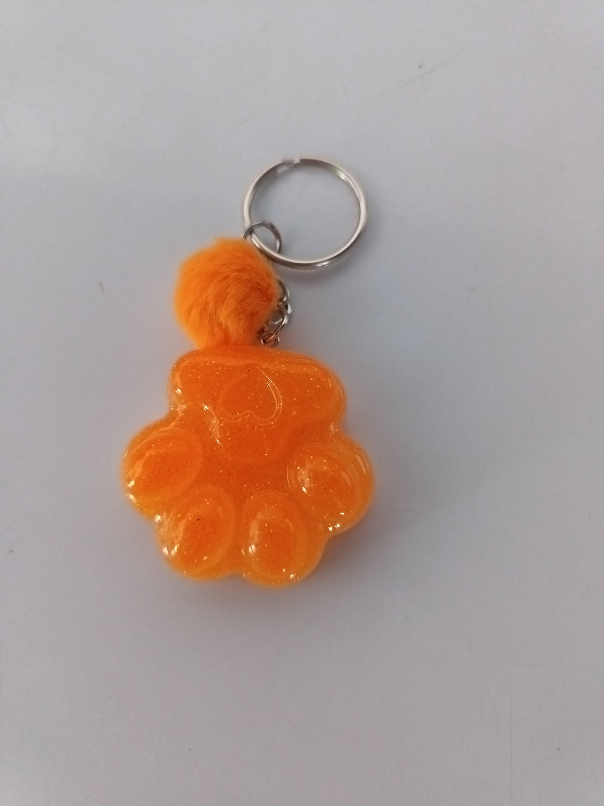 Porte-clé grosse patte de chien sculptée en résine orange vif avec pompon boule de fourrure orange