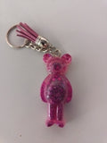 Porte-clé ourson sculpté en résine rose fuchsia pailleté avec pompon suédine rose et chaînette argentée
