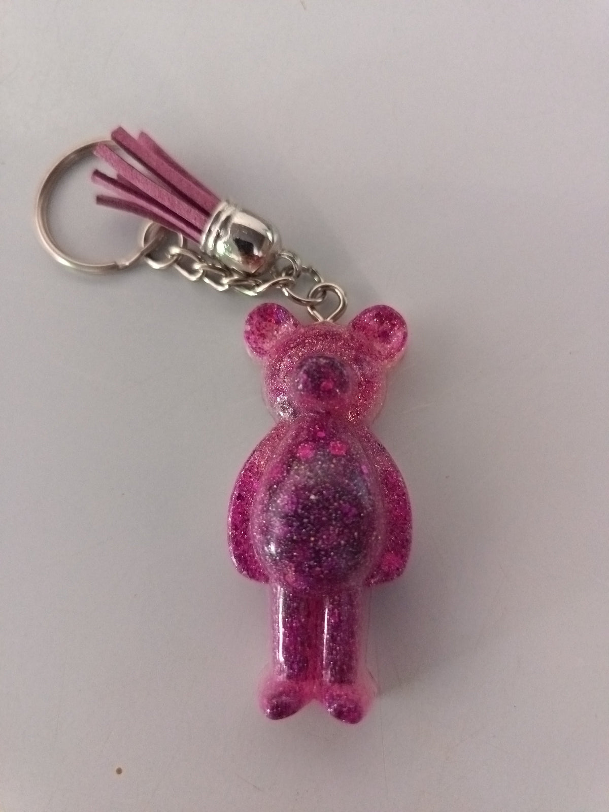 Porte-clé ourson sculpté en résine rose fuchsia pailleté avec pompon suédine rose et chaînette argentée