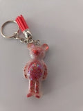 Porte-clé ourson sculpté en résine rose translucide à grosses paillettes irisées avec pompon suédine rouge corail