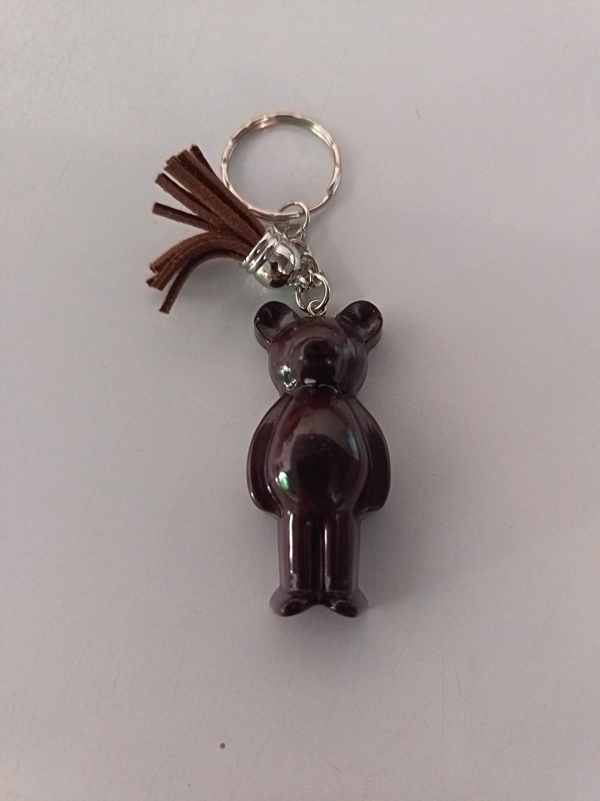 Porte-clé ourson sculpté en résine brun chocolat brillant avec pompon suédine marron et chaînette argentée