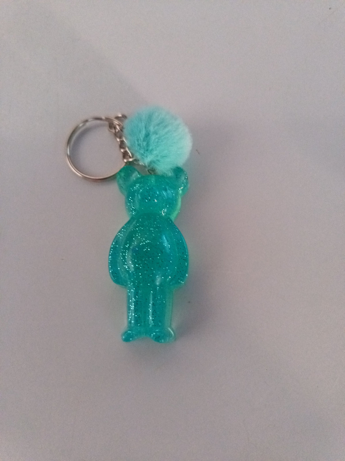 Porte-clé ourson sculpté en résine vert menthe translucide pailleté avec pompon boule de fourrure turquoise