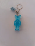Porte-clé ourson sculpté en résine bleu ciel translucide pailleté avec pompon suédine bleu ciel