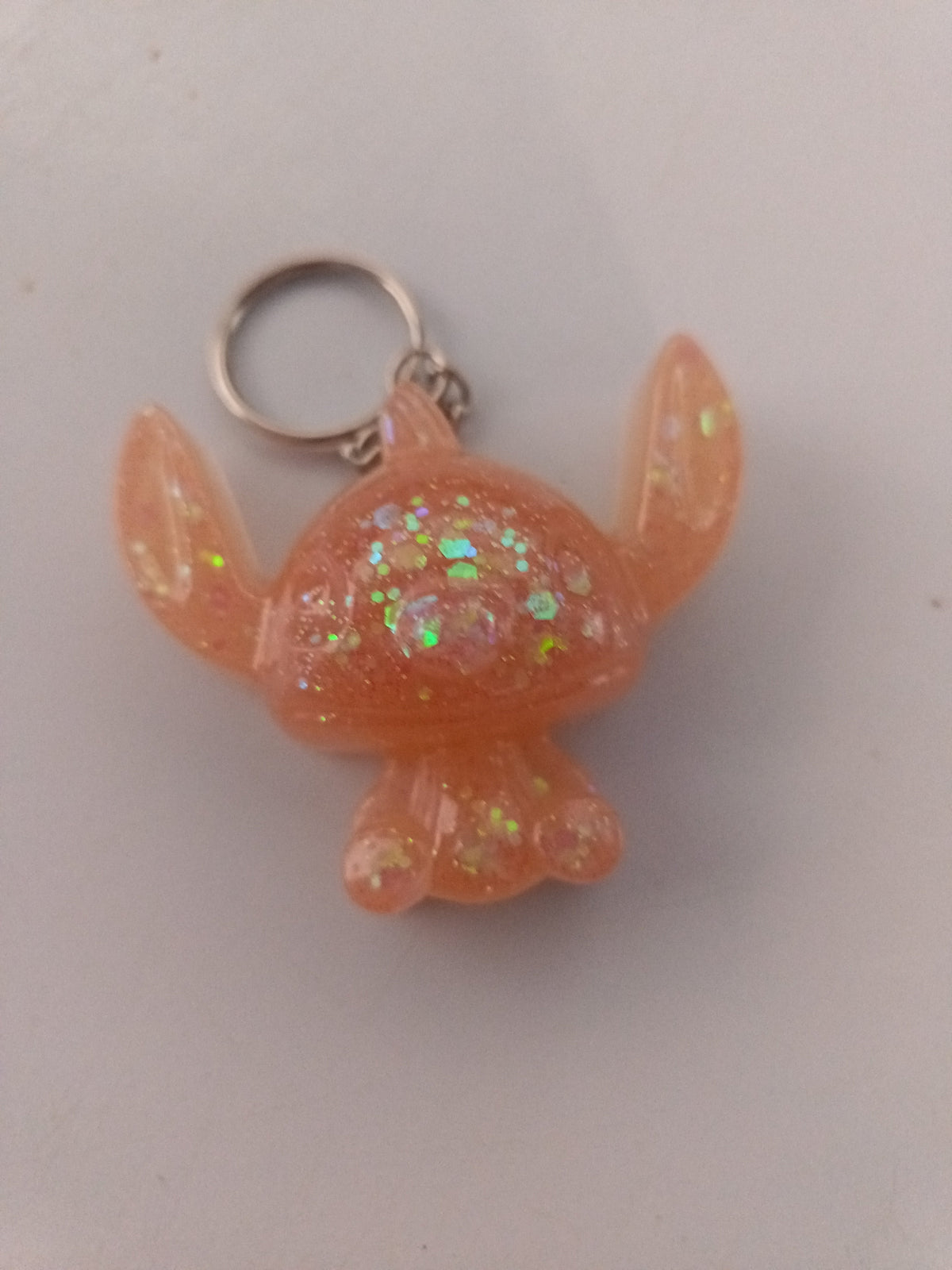 Porte-clé Stitch sculpté en résine pêche-abricot translucide à grosses paillettes holographiques irisées