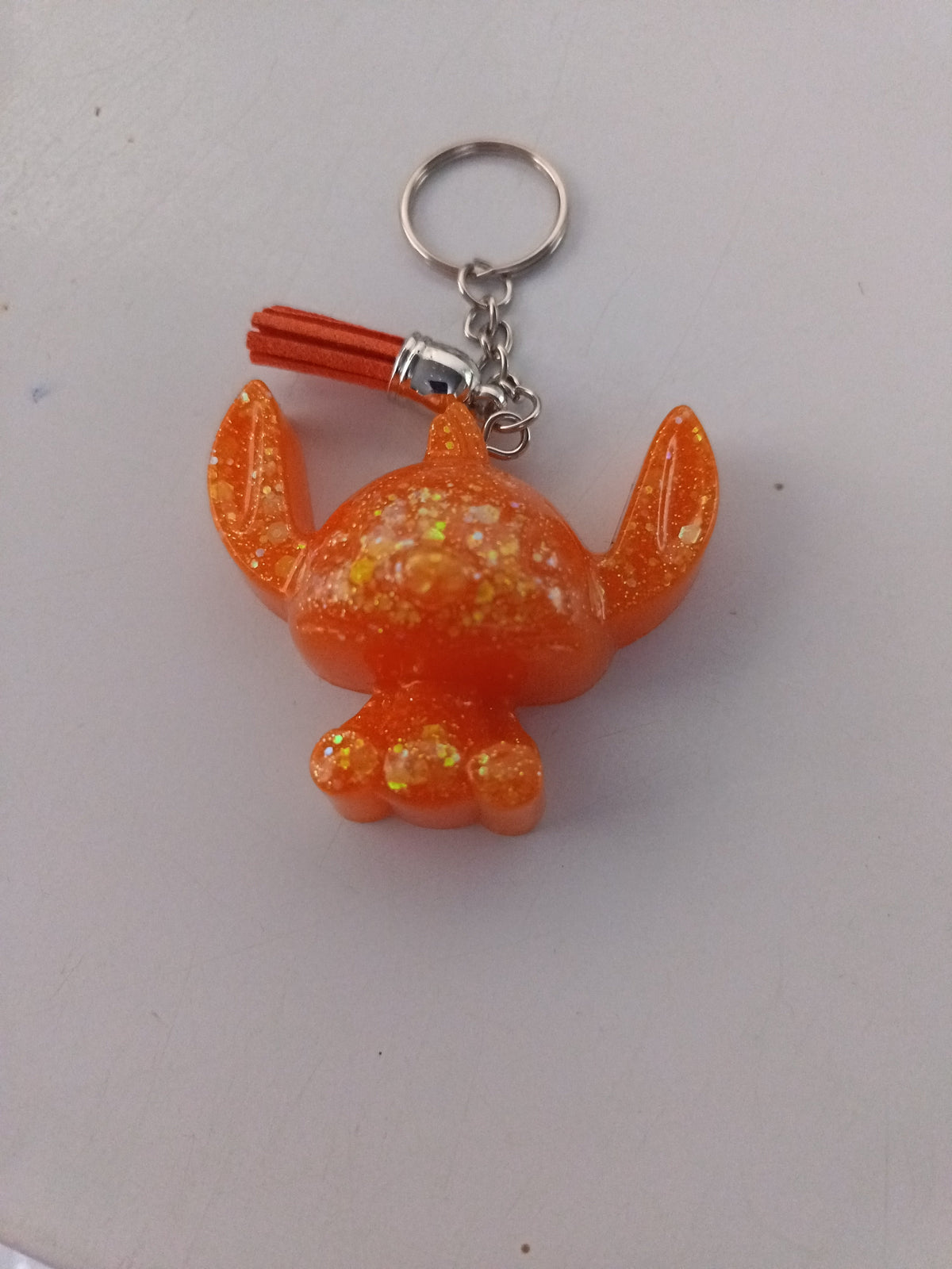 Porte-clé Stitch sculpté en résine orange vif translucide à grosses paillettes holographiques avec pompon suédine orange