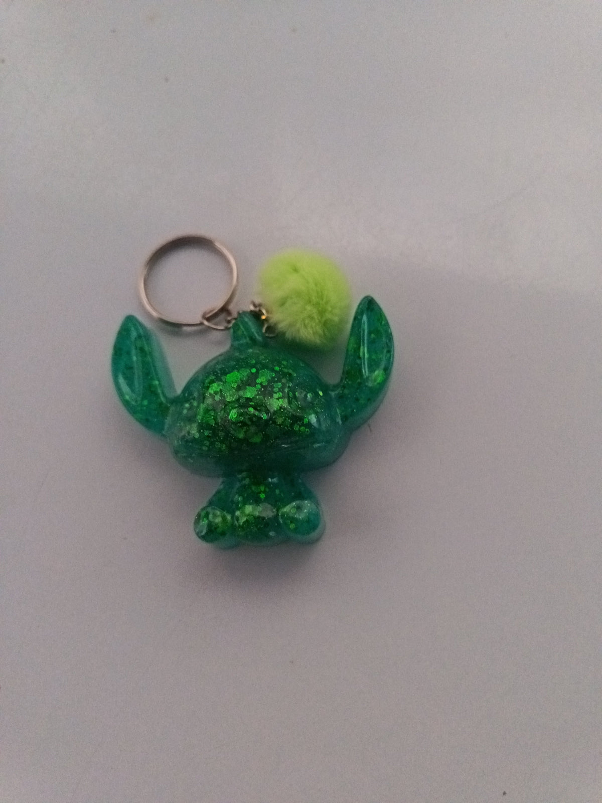Porte-clé Stitch sculpté en résine vert émeraude translucide à grosses paillettes avec pompon boule vert anis
