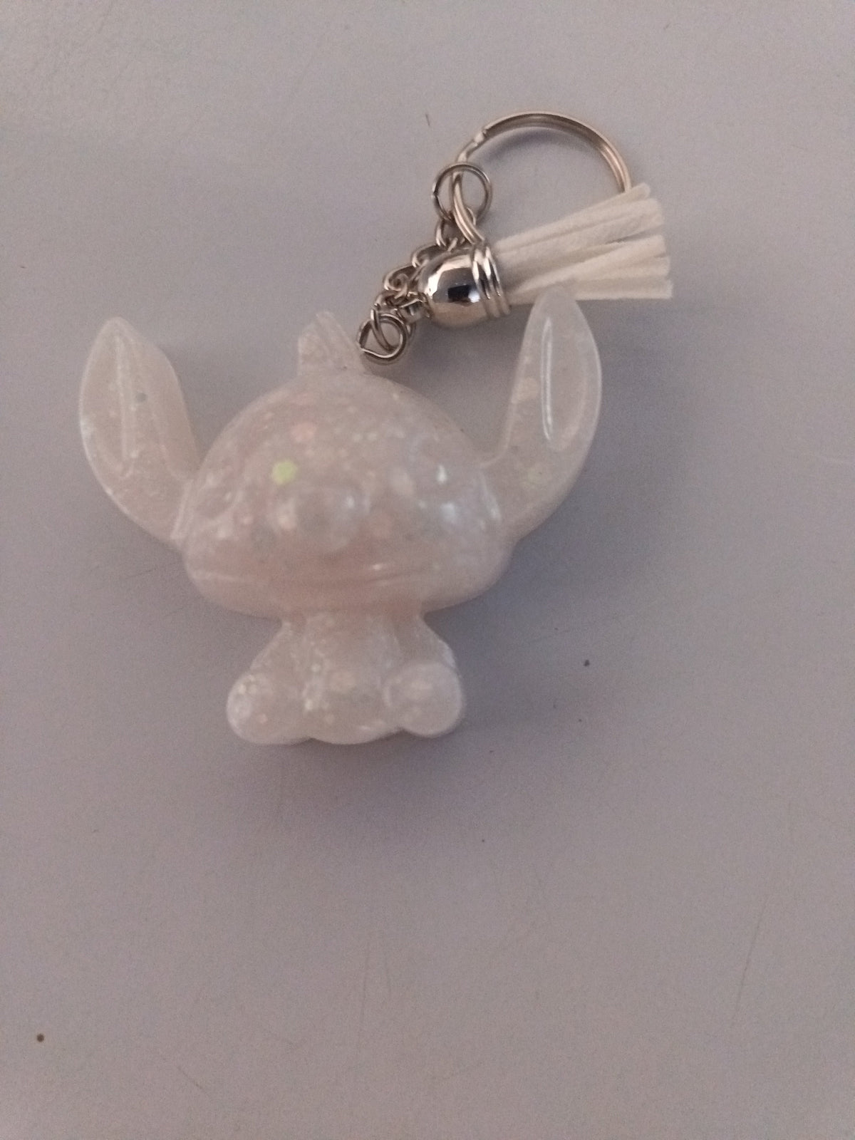 Porte-clé Stitch sculpté en résine blanc opalescent à paillettes holographiques arc-en-ciel avec pompon suédine blanc