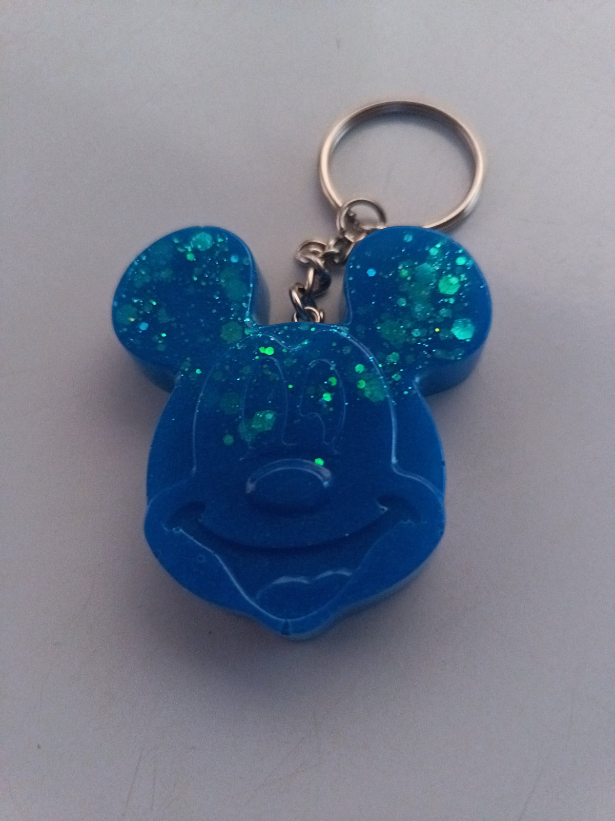 Porte-clé tête de Mickey sculptée en résine bleu électrique translucide à grosses paillettes turquoise holographiques