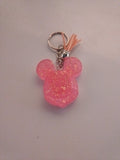 Porte-clé tête de Mickey sculptée en résine rose bonbon translucide à grosses paillettes irisées avec pompon suédine pêche