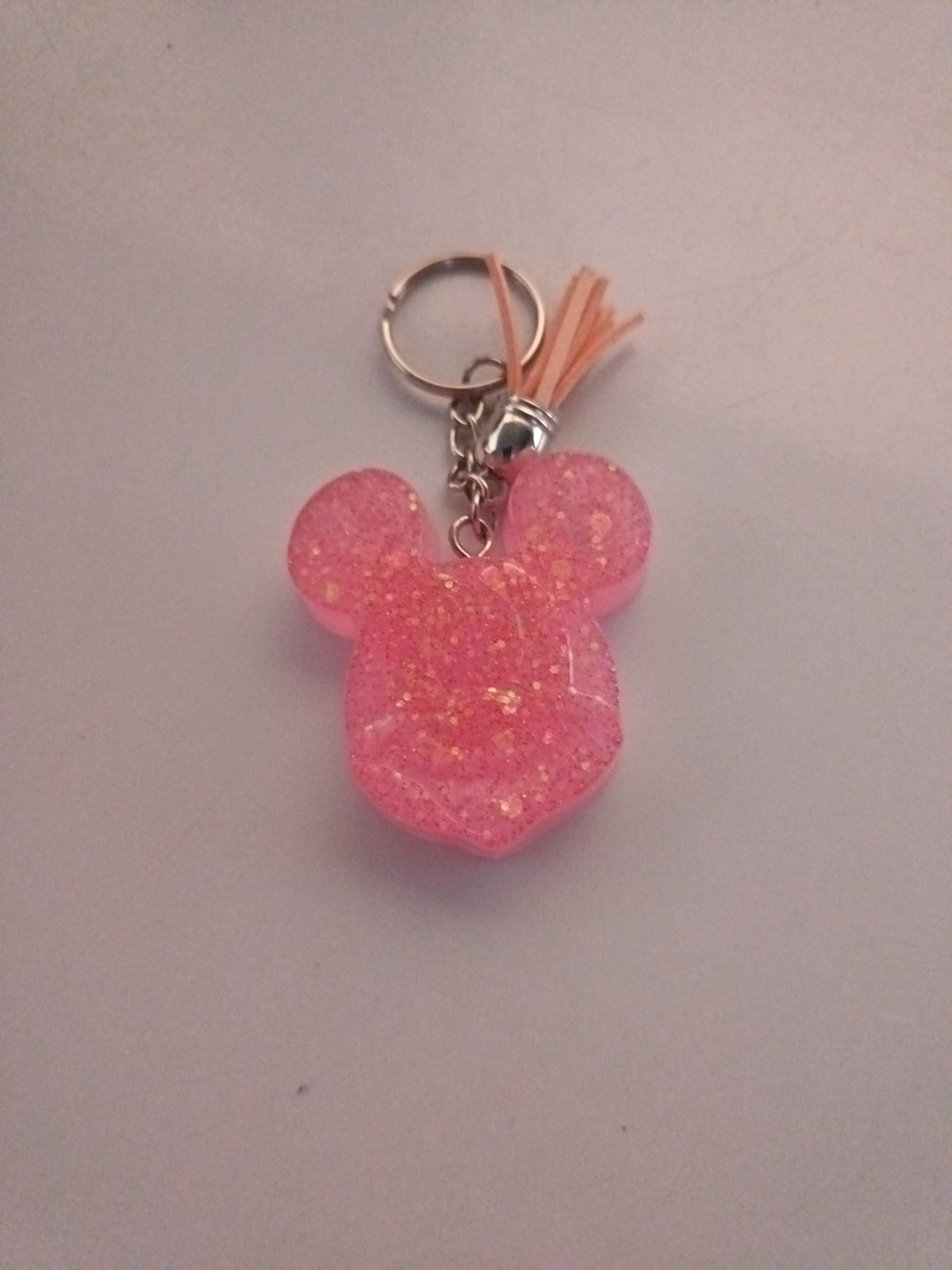 Porte-clé tête de Mickey sculptée en résine rose bonbon translucide à grosses paillettes irisées avec pompon suédine pêche