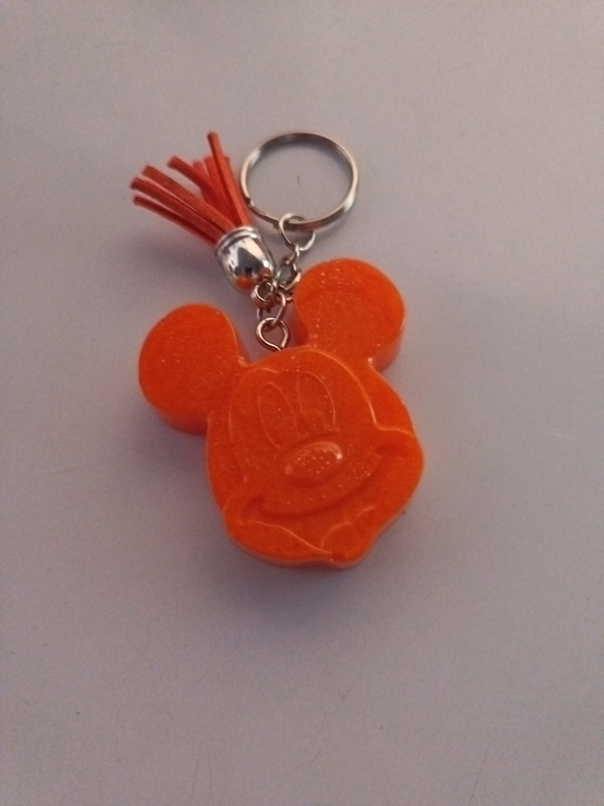 Porte-clé Mickey en résine orange opaque avec visage sculpté détaillé et pompon suédine rouge