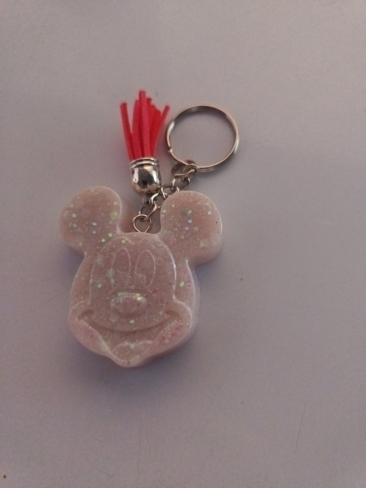 Porte-clé Mickey en résine blanc nacré opalescent avec visage sculpté détaillé et pompon suédine rouge vif