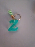 Porte-clé lettre Z sculptée en résine turquoise ultra-pailleté avec pompon suédine vert menthe et chaînette dorée