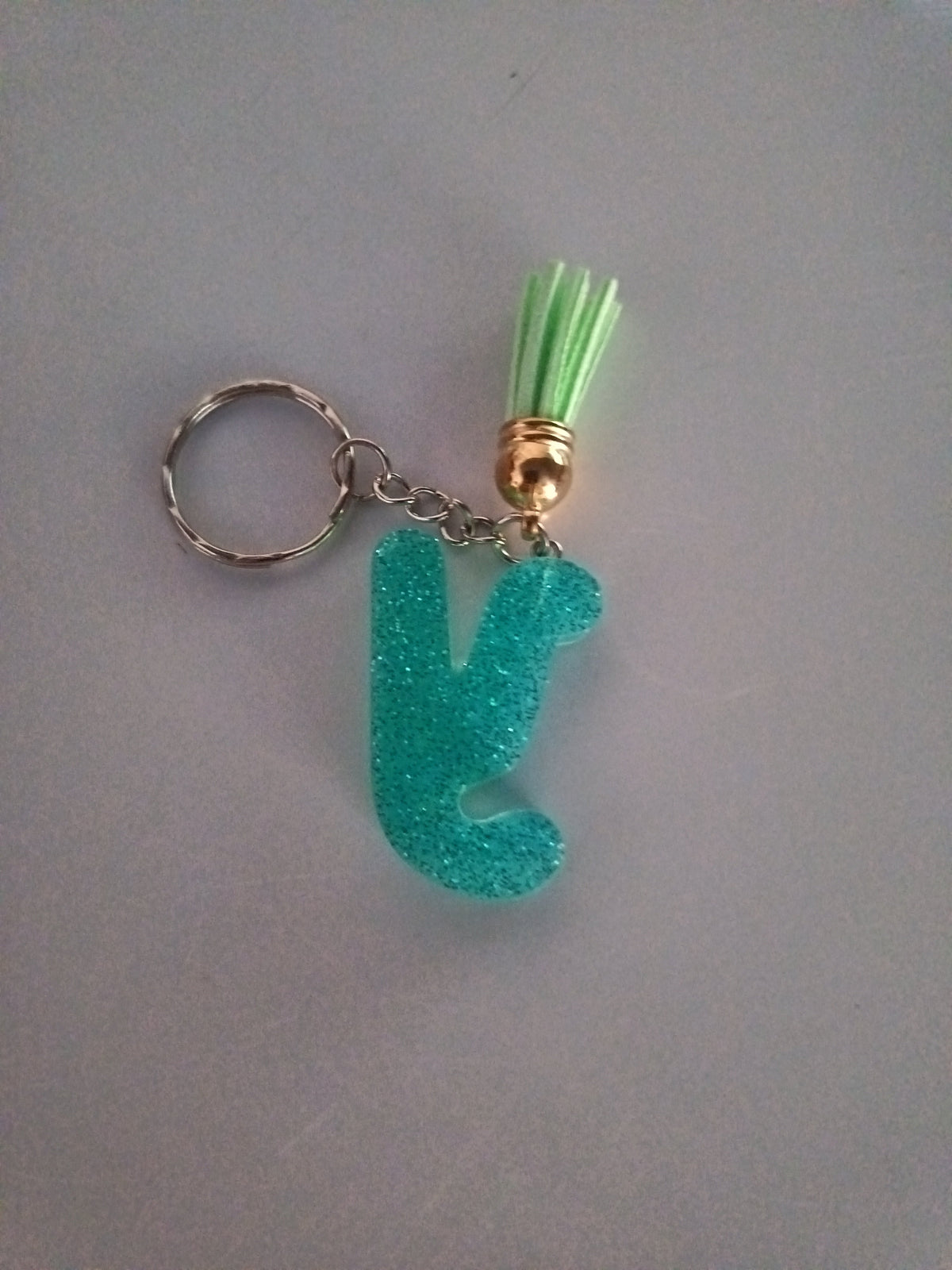 Porte-clé lettre Y sculptée en résine turquoise ultra-pailleté avec pompon suédine vert anis et chaînette dorée