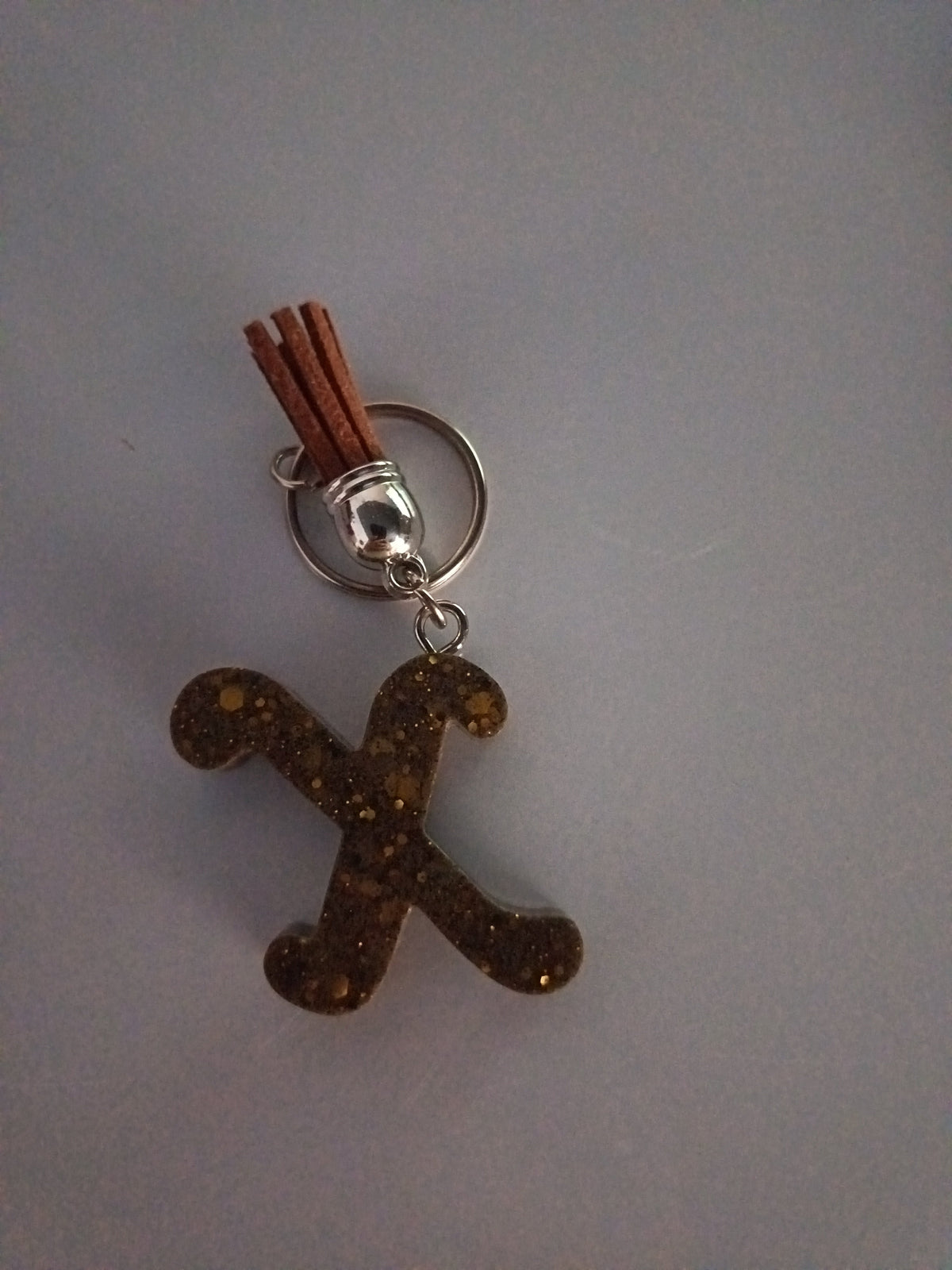 Porte-clé lettre X sculptée en résine brun doré à grosses paillettes cuivrées avec pompon suédine terracotta