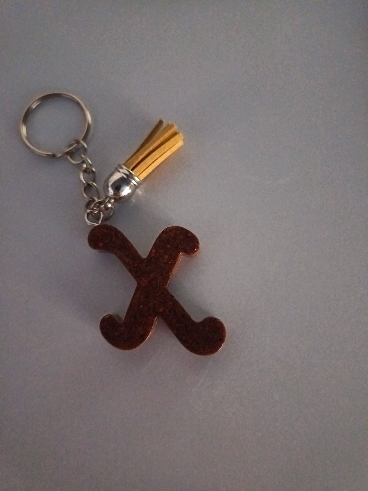 Porte-clé lettre X sculptée en résine brun chocolat pailleté avec pompon suédine jaune doré et chaînette argentée