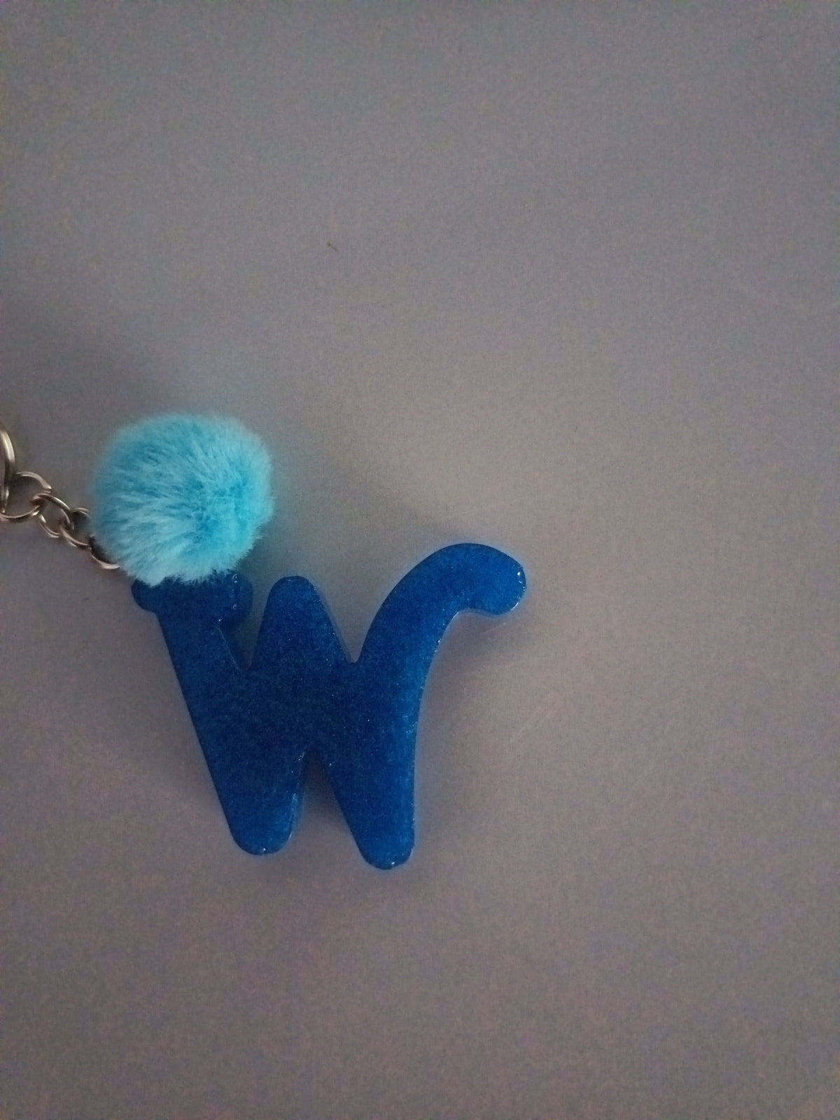 Porte-clé lettre W sculptée en résine bleu roi pailleté avec pompon boule de fourrure bleu ciel et chaînette argentée