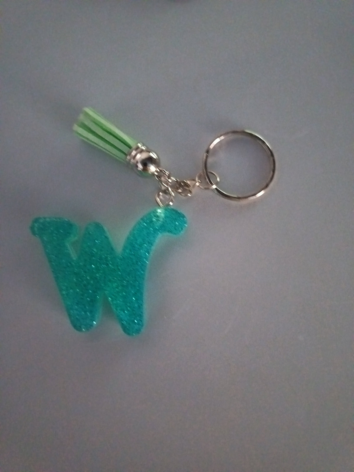 Porte-clé lettre W sculptée en résine turquoise ultra-pailleté avec pompon suédine vert menthe et chaînette argentée