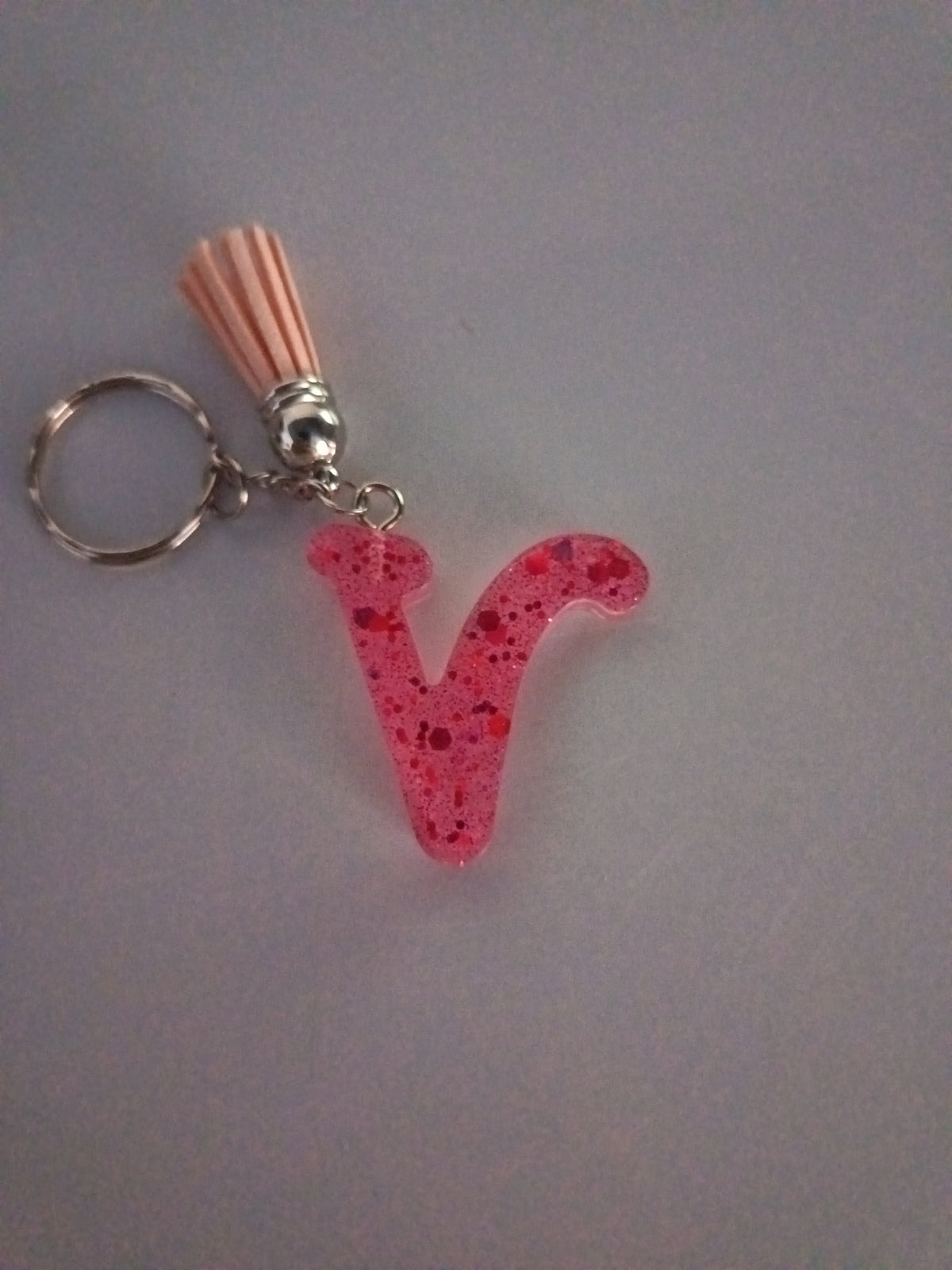 Porte-clé lettre V sculptée en résine rose fuchsia translucide à grosses paillettes rouges avec pompon suédine rose saumon