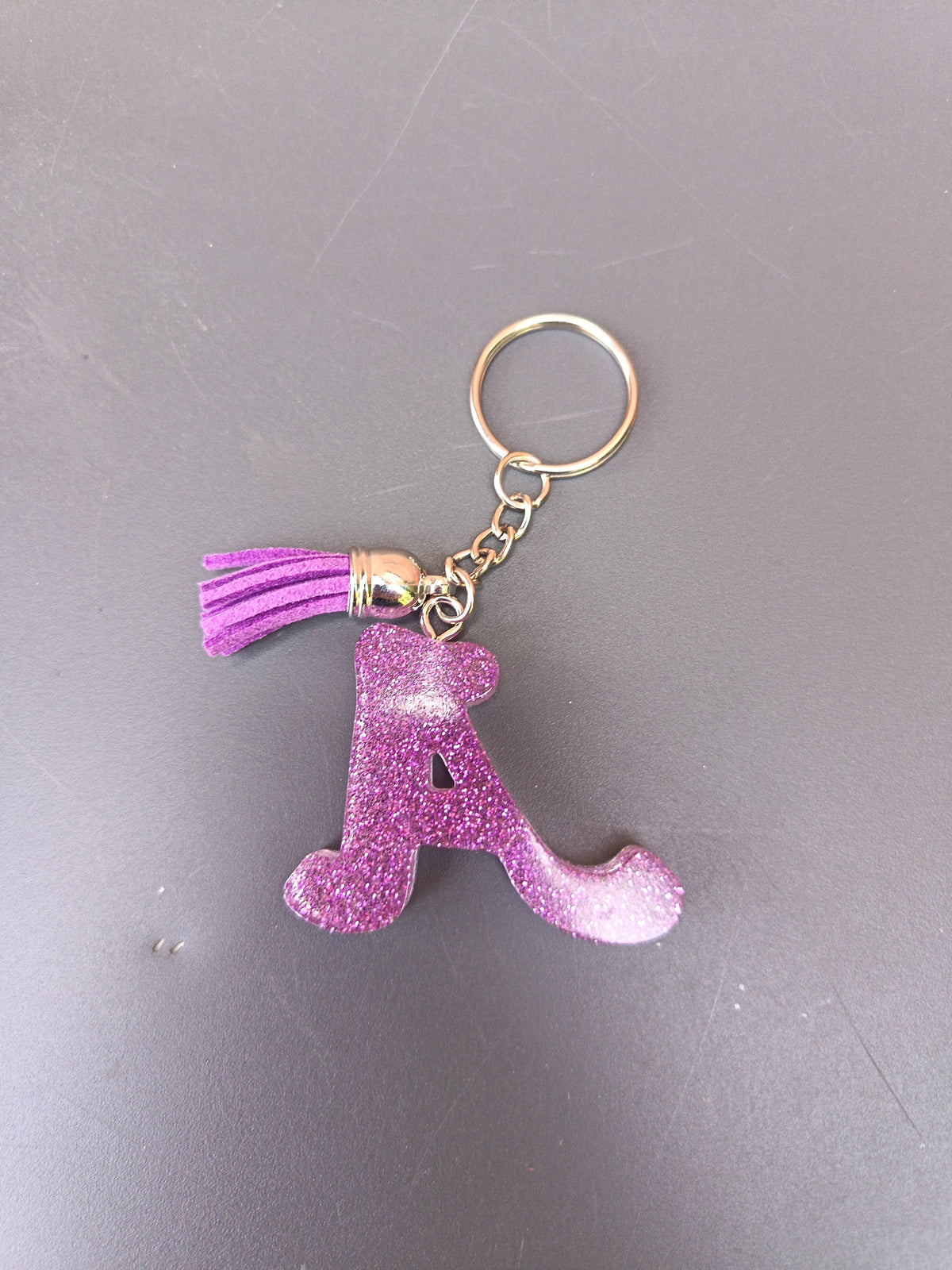 Porte-clé lettre A sculptée en résine violet fuchsia ultra-pailleté avec pompon suédine violet et anneau doré