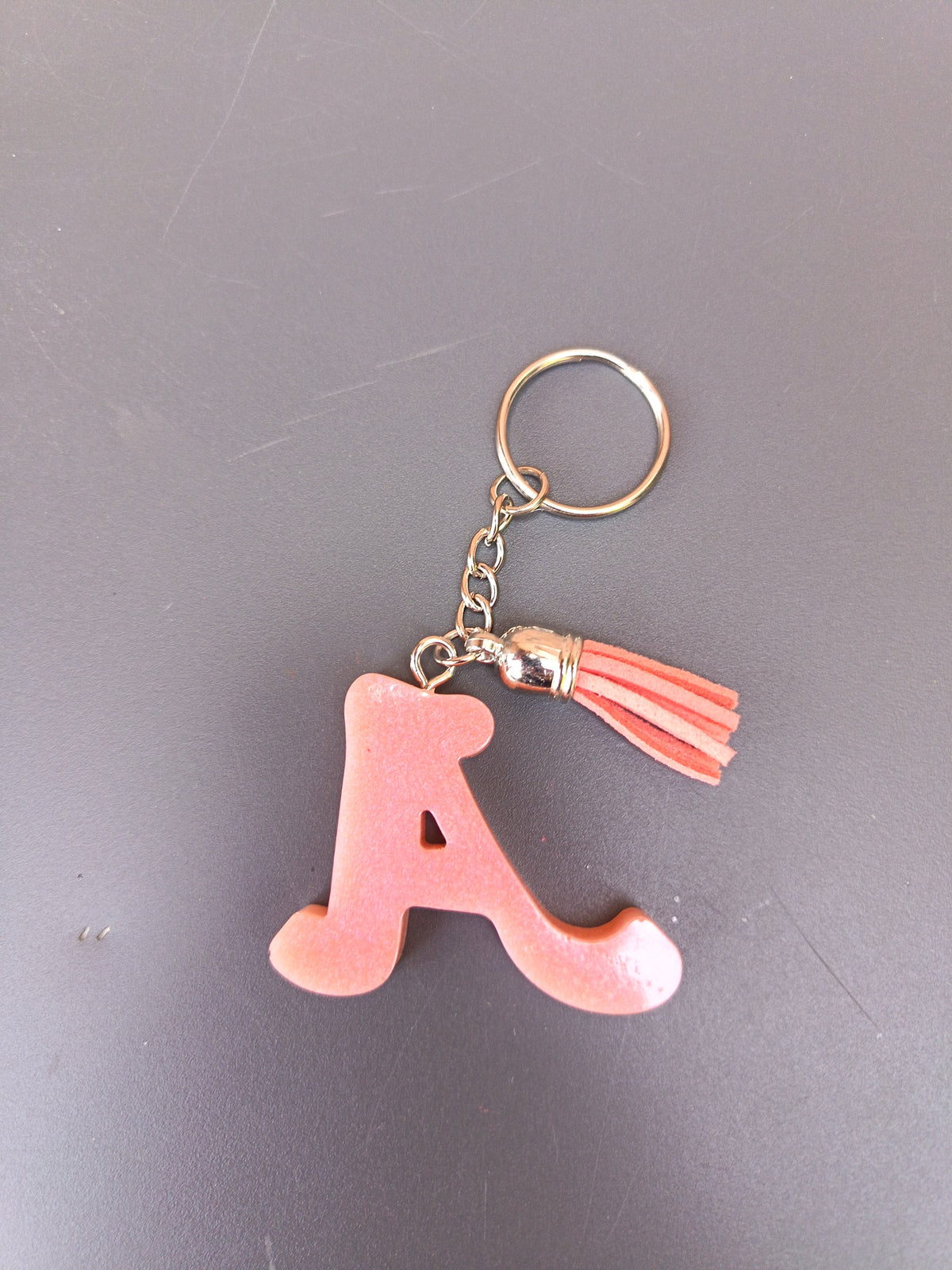 Porte-clé lettre A sculptée en résine rose saumon opaque mat avec pompon suédine rose saumon et chaînette argentée