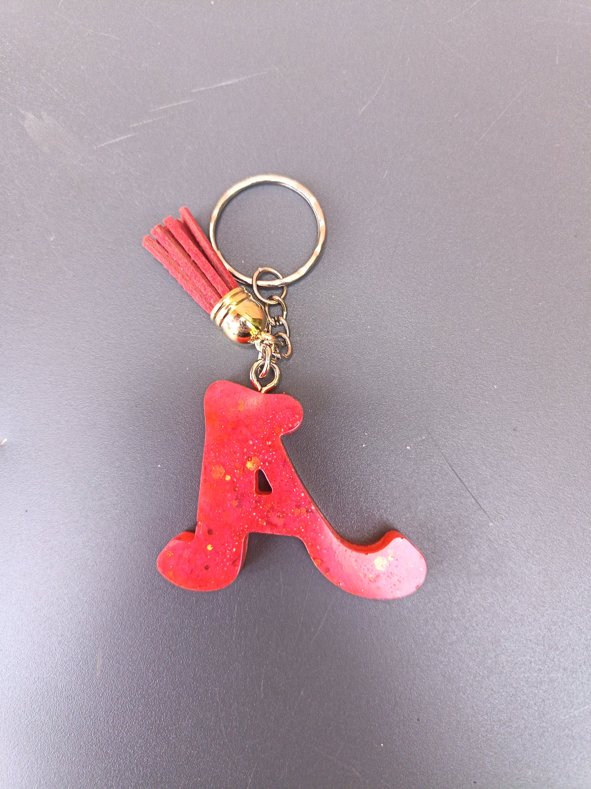 Porte-clé lettre A sculptée en résine rouge vif à micro-paillettes dorées avec pompon suédine rouge et anneau doré