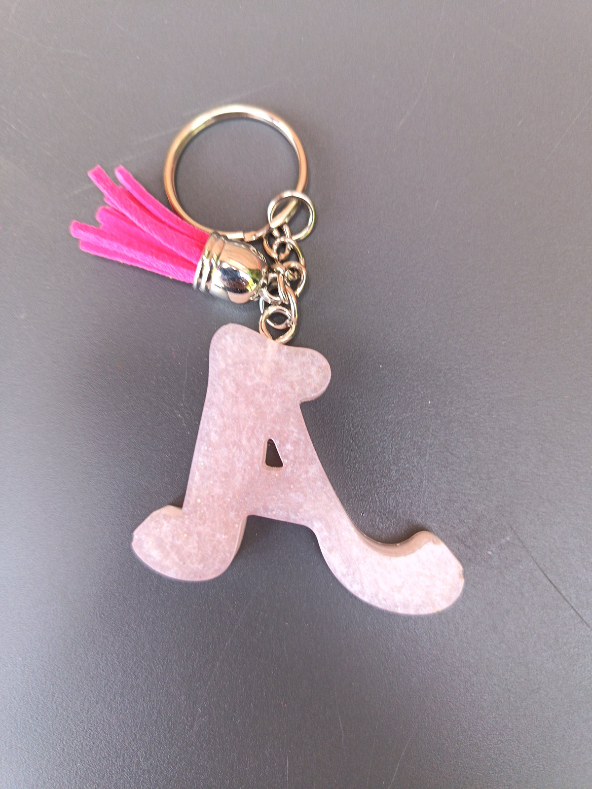 Porte-clé lettre A sculptée en résine rose poudré givré nacré avec pompon suédine rose fuchsia vif et anneau doré
