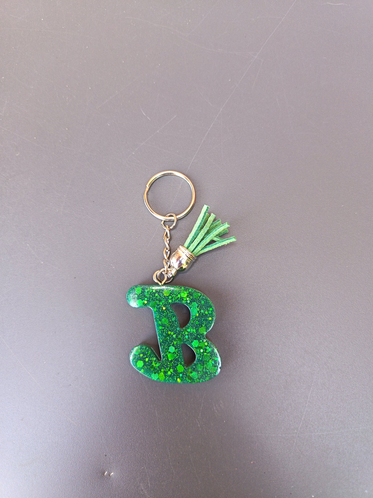Porte-clé lettre B sculptée en résine vert émeraude translucide à grosses paillettes holographiques avec pompon suédine vert menthe