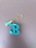Porte-clé lettre B sculptée en résine bleu turquoise ultra-pailleté avec pompon suédine vert menthe et chaînette dorée