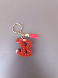 Porte-clé lettre B sculptée en résine rouge vif à grosses paillettes holographiques avec pompon suédine rouge corail