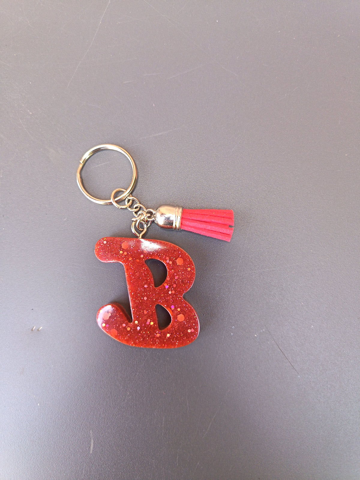 Porte-clé lettre B sculptée en résine rouge vif à grosses paillettes holographiques avec pompon suédine rouge corail