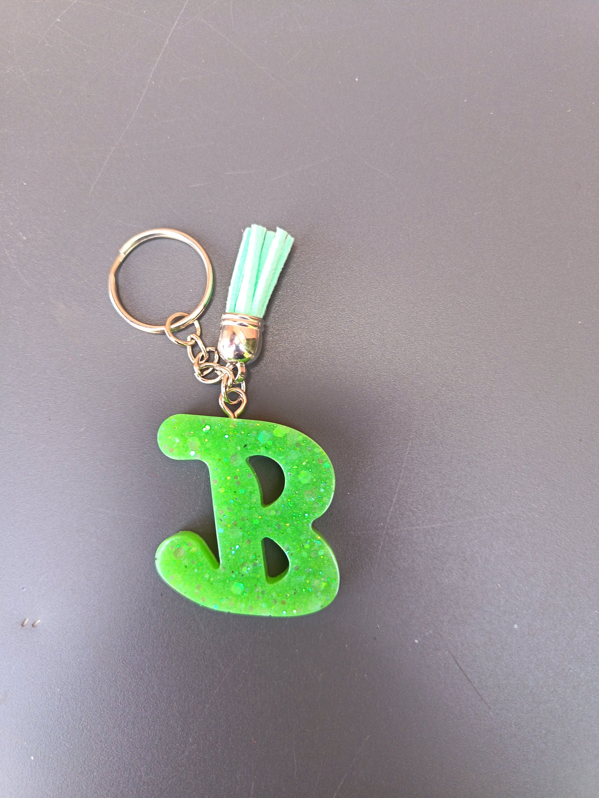 Porte-clé lettre B sculptée en résine vert anis fluo à paillettes holographiques avec pompon suédine vert menthe clair et chaînette dorée