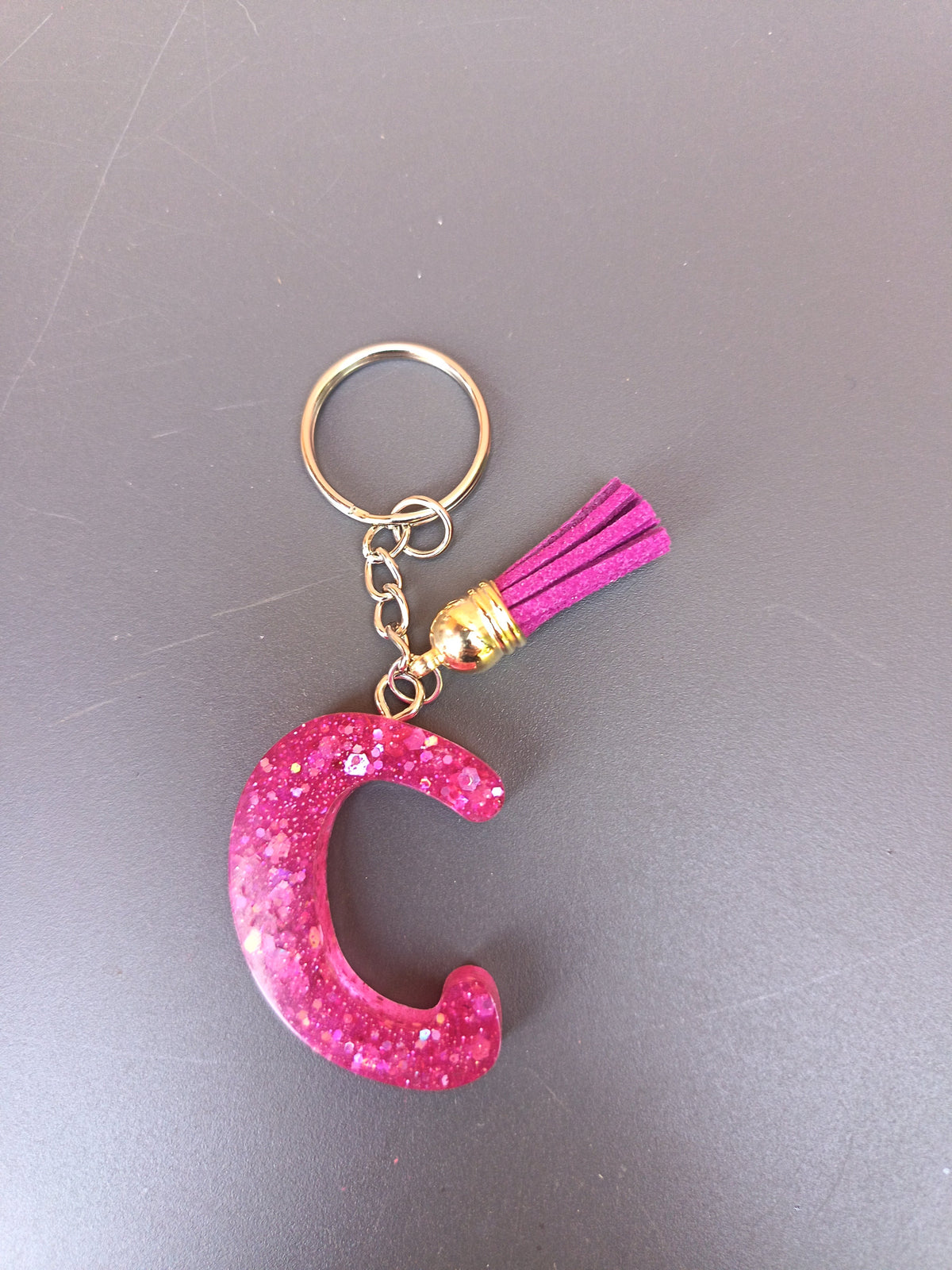Porte-clé lettre C sculptée en résine rose fuchsia à grosses paillettes holographiques avec pompon suédine fuchsia et chaînette dorée