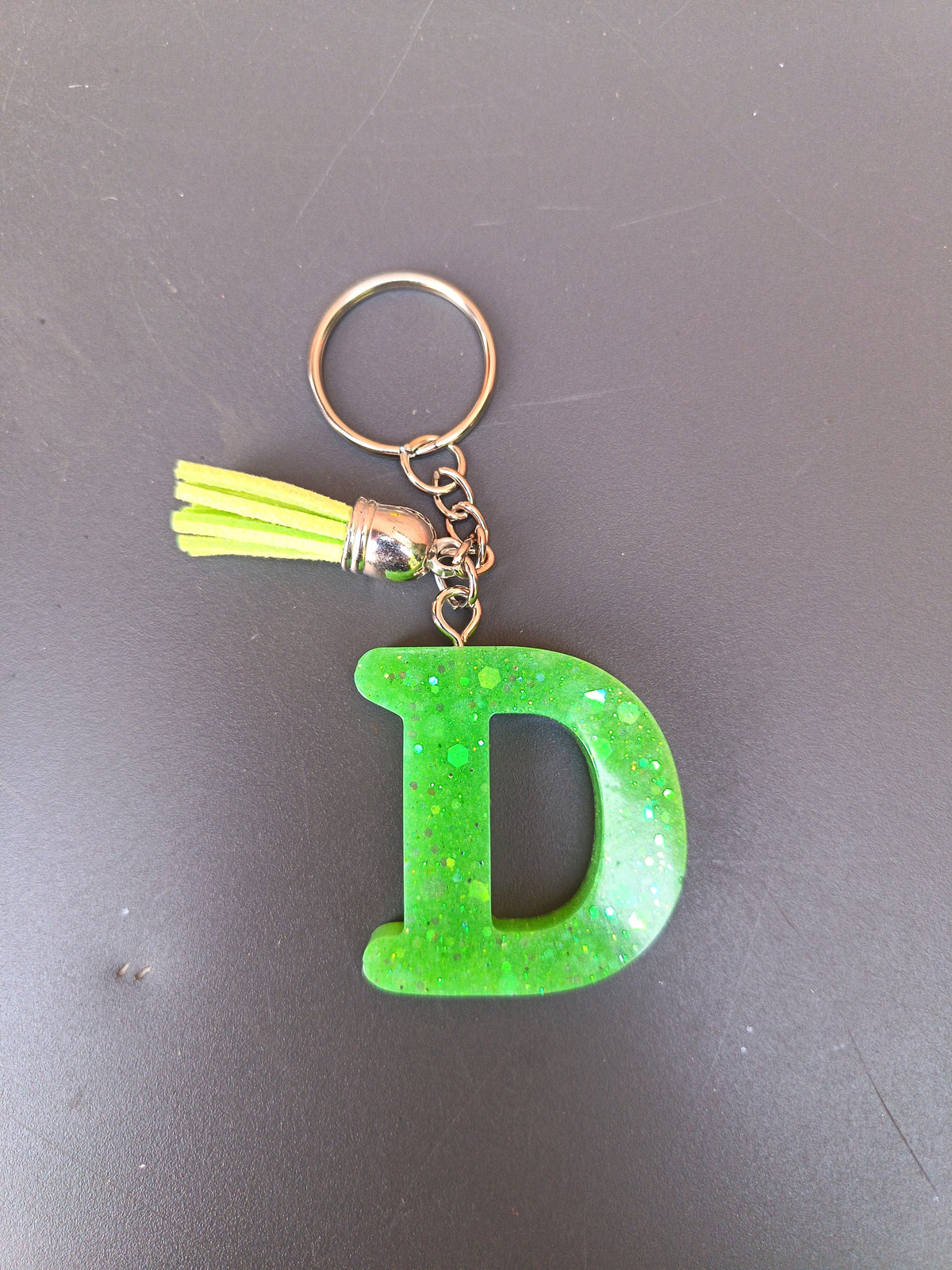 Porte-clé lettre D sculptée en résine vert fluo à grosses paillettes holographiques avec pompon suédine jaune fluo et chaînette argentée