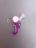 Porte-clé lettre F sculptée en résine violet fuchsia ultra-pailleté avec pompon boule fourrure rose lilas et mini-pompon suédine lilas et chaînette dorée
