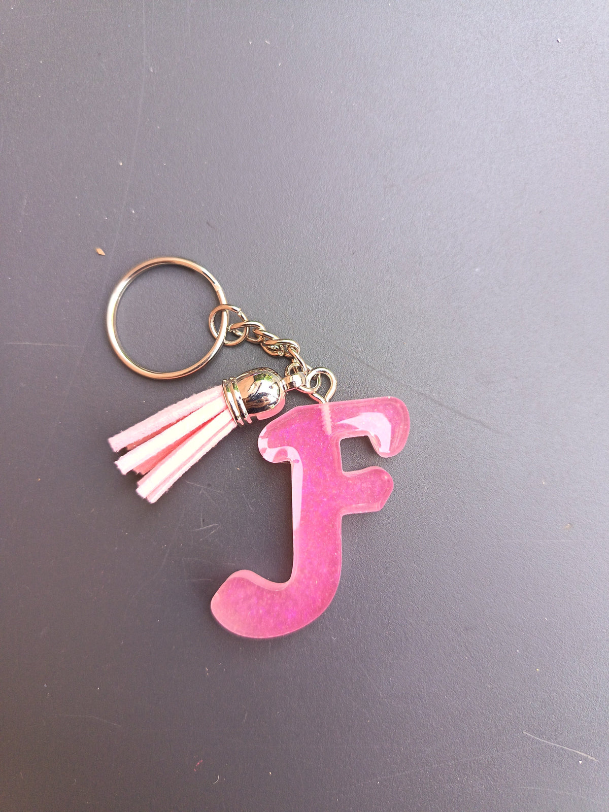 Porte-clé lettre F sculptée en résine rose fuchsia translucide nacré avec pompon suédine rose poudré et chaînette dorée